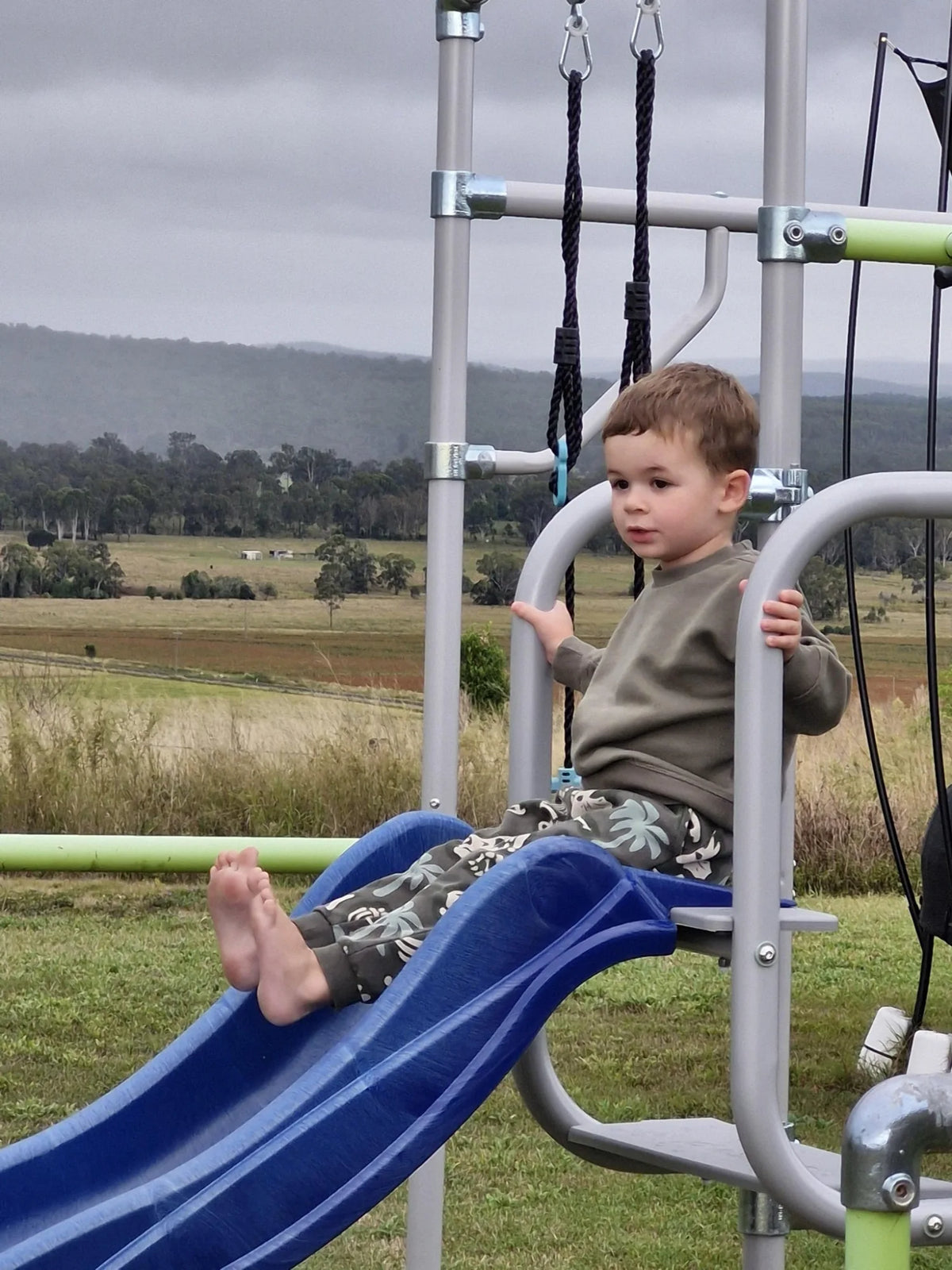 Child using a slide attached to a Growplay frame with the Slide Mount — slide sold separately